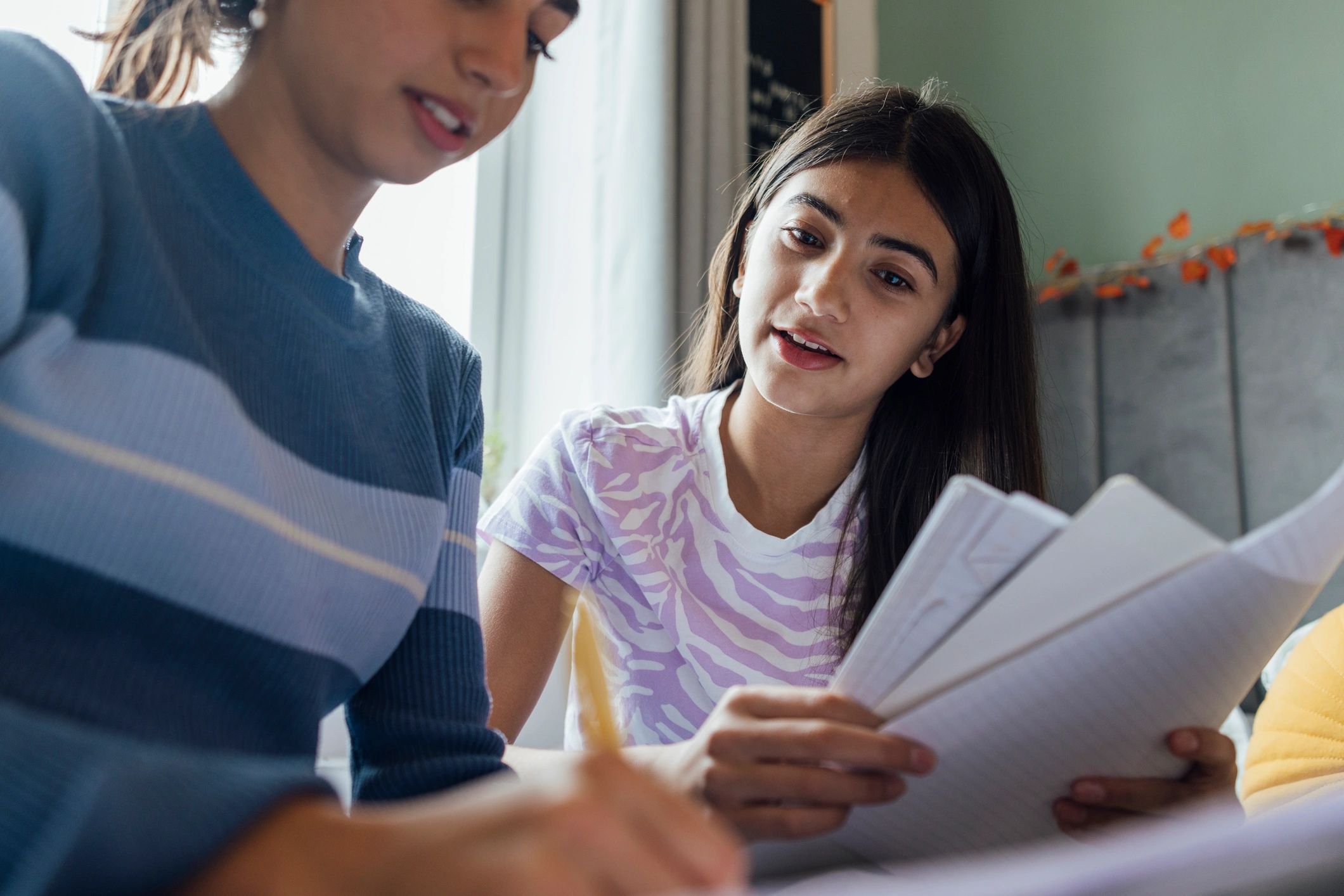 Older student helping a younger learner with schoolwork