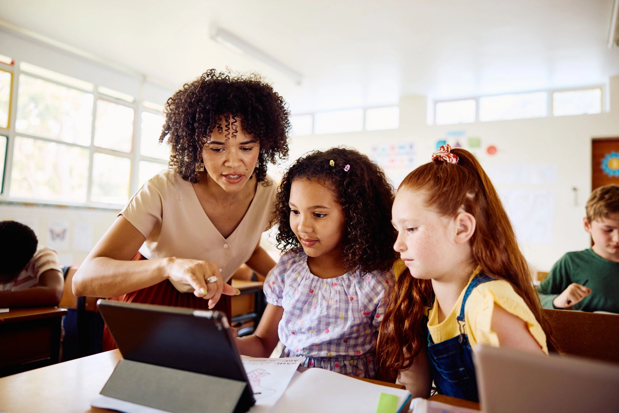 Teacher guiding two primary school students during a learning session