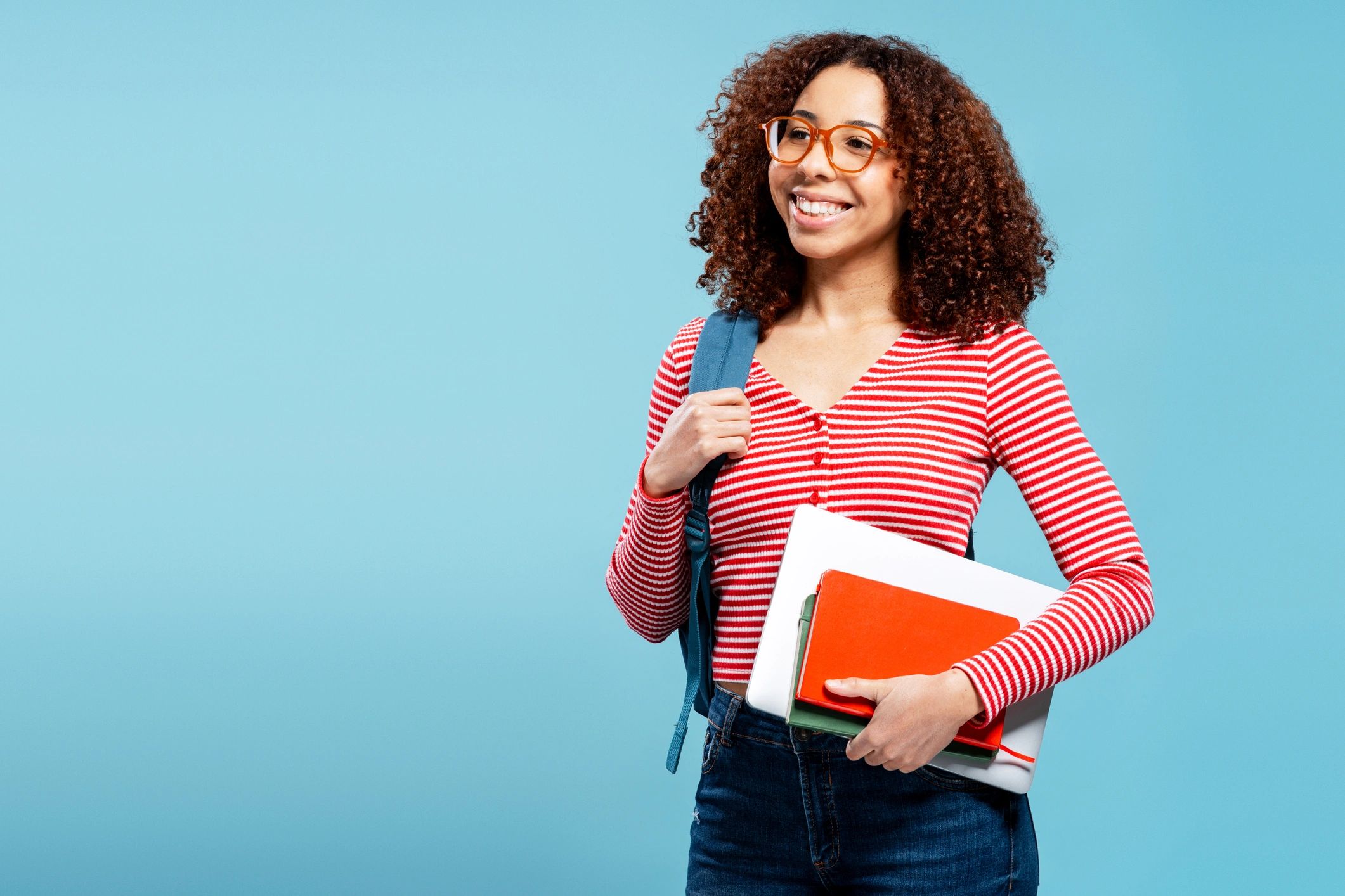 Student carrying books and smiling confidently